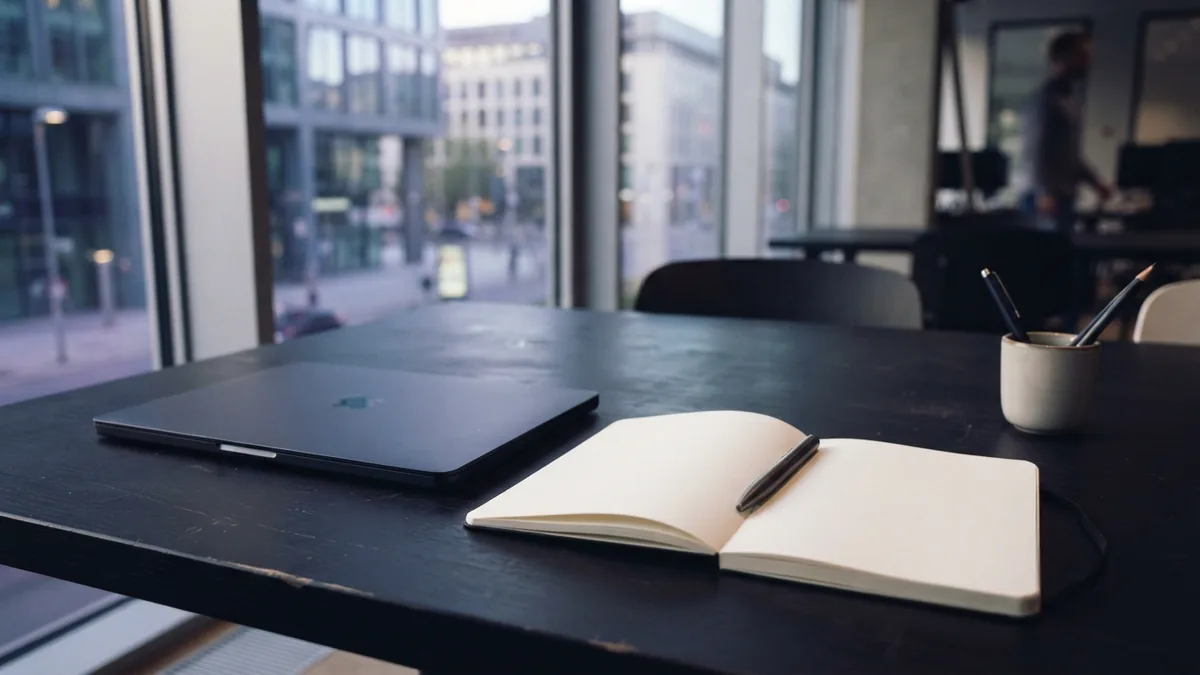 Neat office workspace with a notebook and laptop for planning customer follow-ups